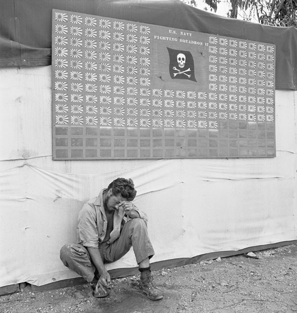 "Tired member of VF-17 pauses under the squadron scoreboard at Bougainville