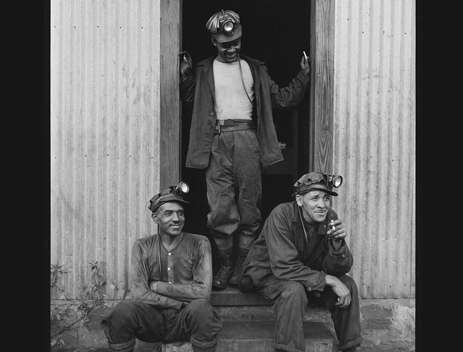 Three coal miners in the doorway of the lamp house