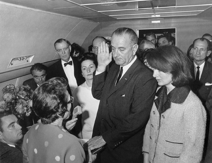 "Lyndon Johnson takes the Presidential oath of office aboard Air Force One..."
