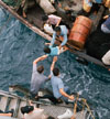 South China Sea... Crewman of the amphibious cargo ship U.S.S. Durham (LKA-114) take Vietnamese refugees