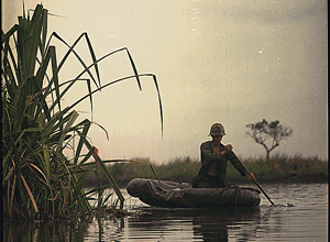 Soldier paddles a three-man assault boat down a canal in Vietnam