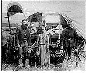 A family poses with the wagon in which they live and travel daily during their pursuit of a homestead, 1886.
