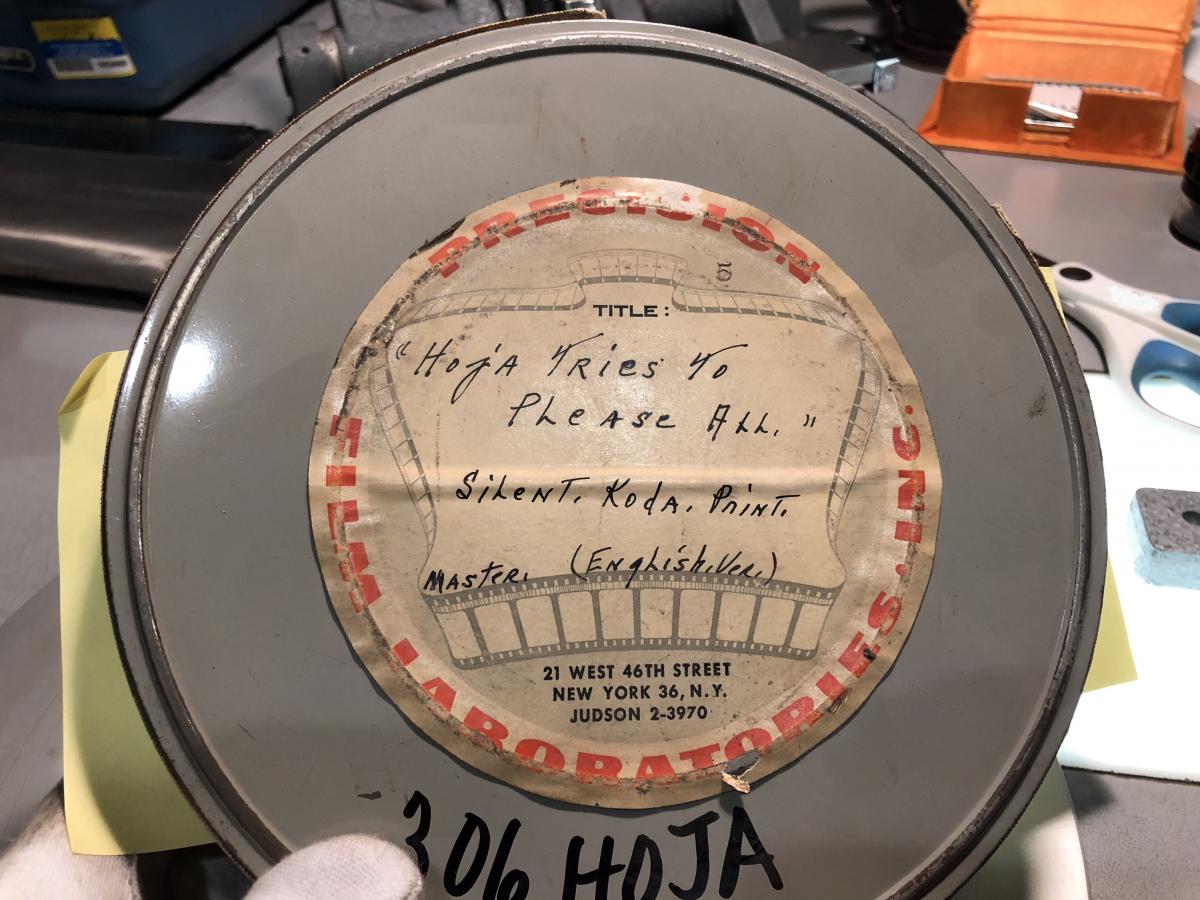 Film can with a label giving the title as "The Hoja Tries to Please All" and identifying the film as a silent Kodachrome print of the English version.
