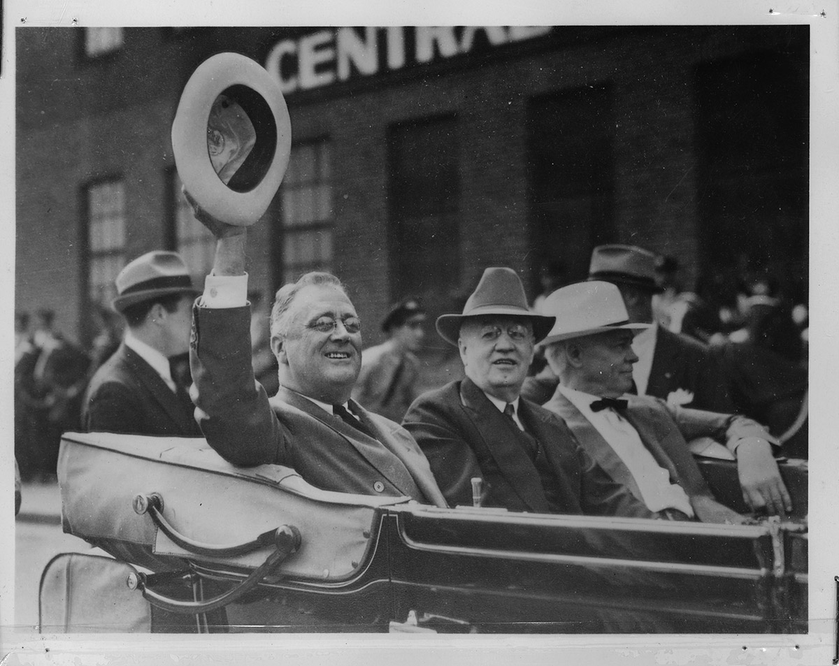 President Franklin Roosevelt waves while sitting in an open car