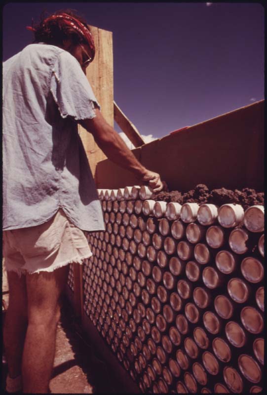 A construction worker uses empty beer cans as building materials 