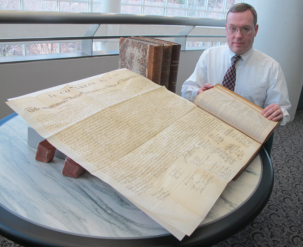 Jeffery Hartley unfolds a Stone engraving in an American Archives volume
