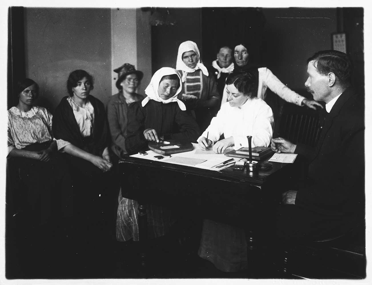 Immigration station officials examine recent arrivals at Ellis Island, New York, ca. 1920
