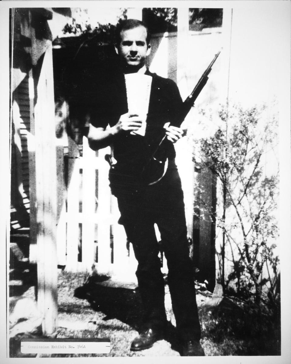 Oswald poses in his backyard with a rifle Oswald poses in his backyard with a rifle