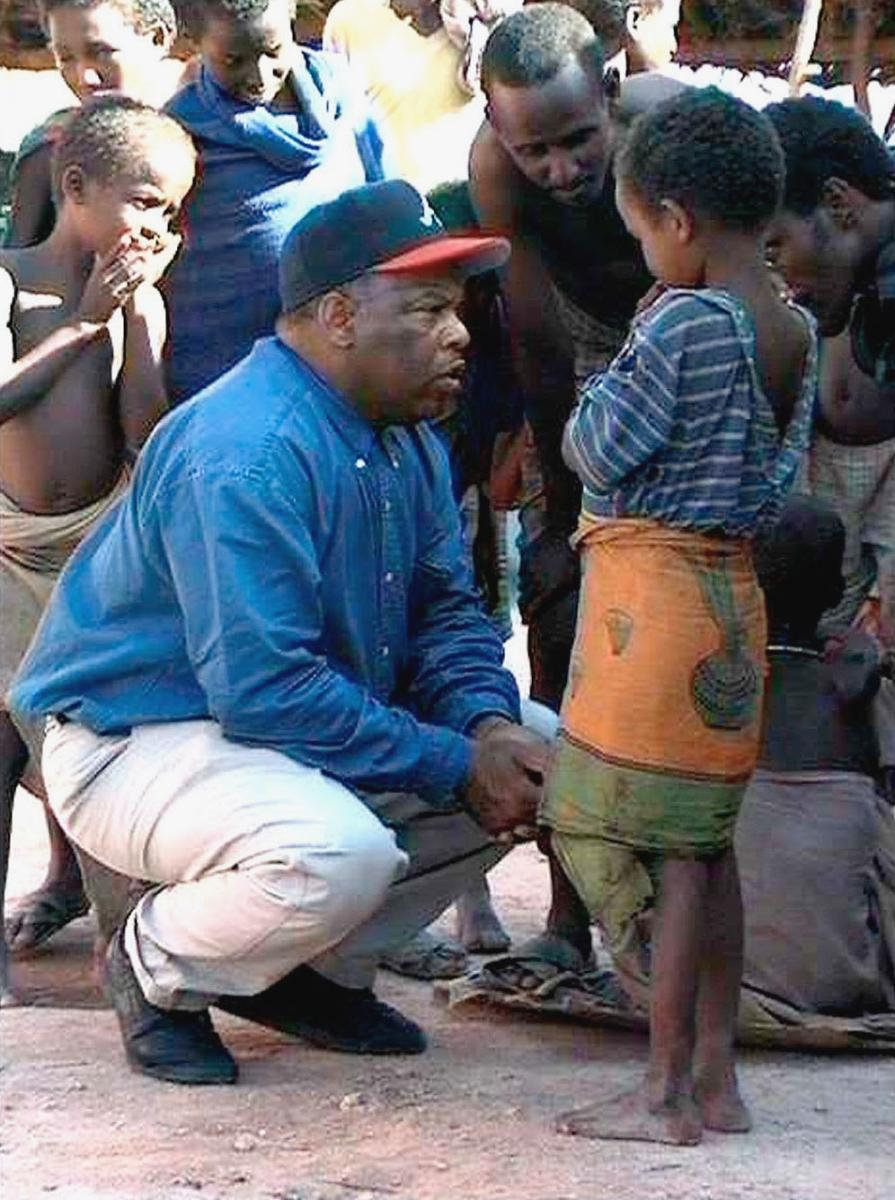 John Lewis kneeling down to speak with a Somali child
