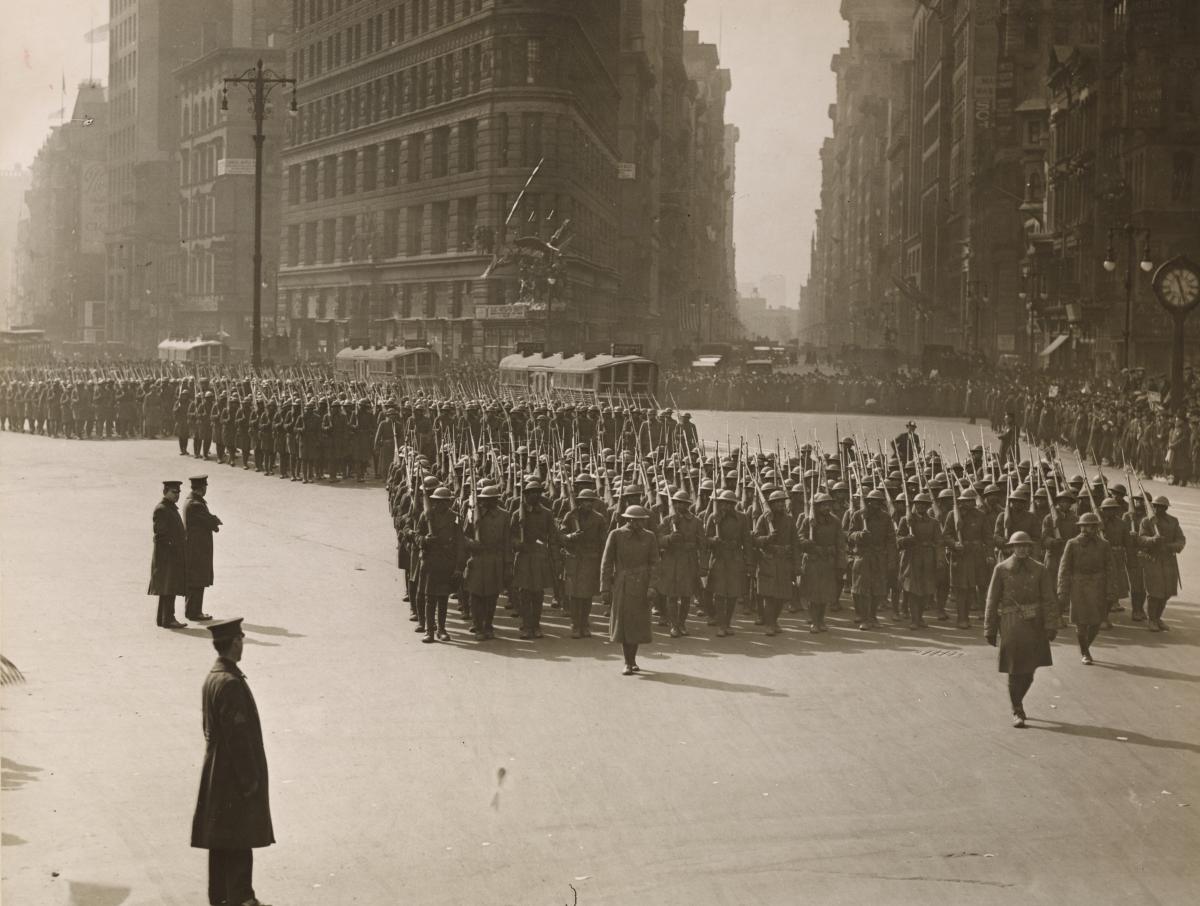 a unit of troops marching in New York City in front of the Flat Iron building