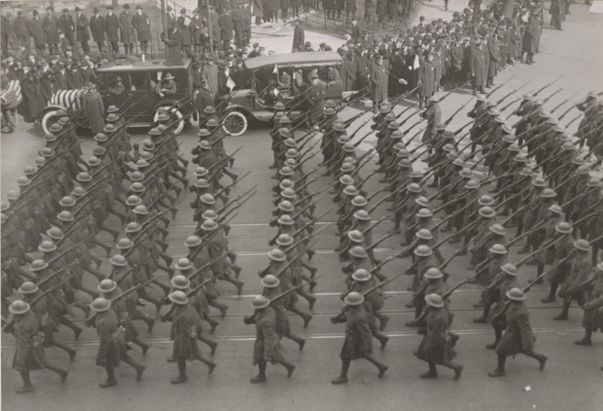 columns of soldiers marching in the street with people lining the street