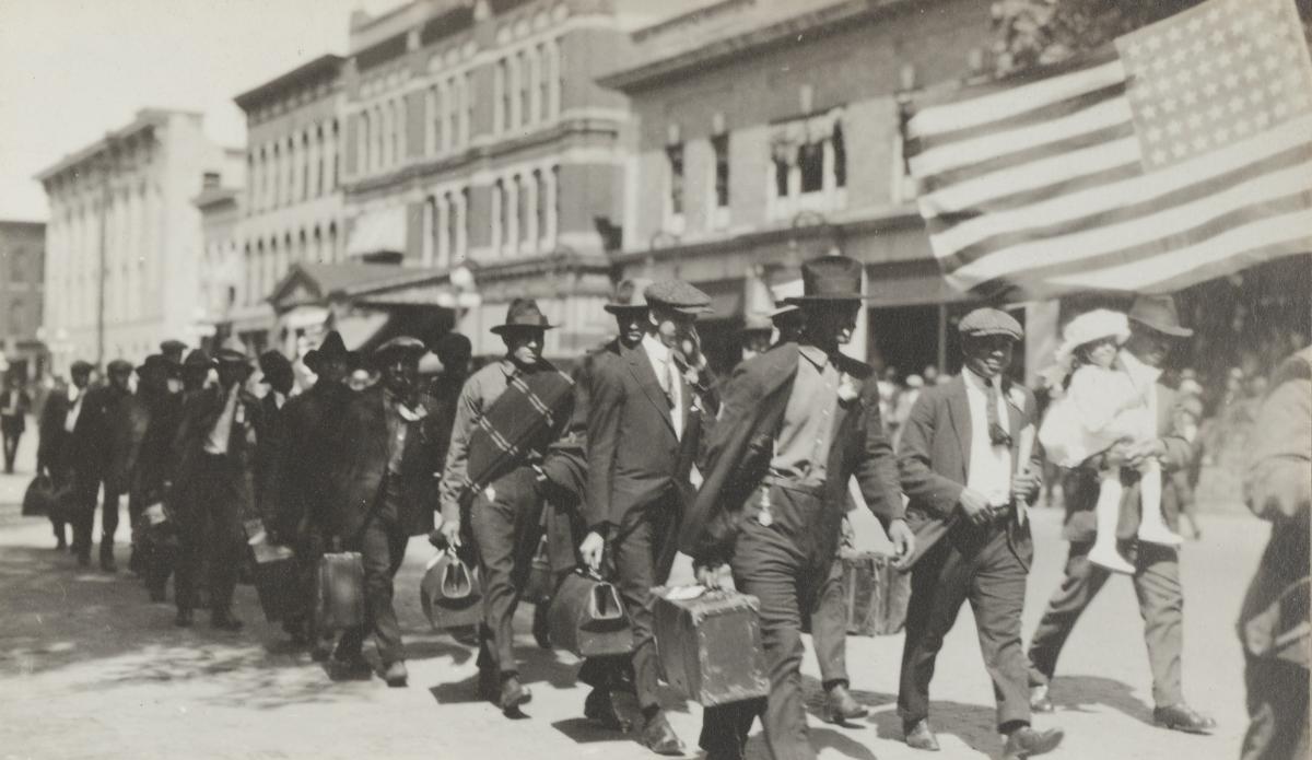 men dressed in civilian clothing walking in pairs out of town