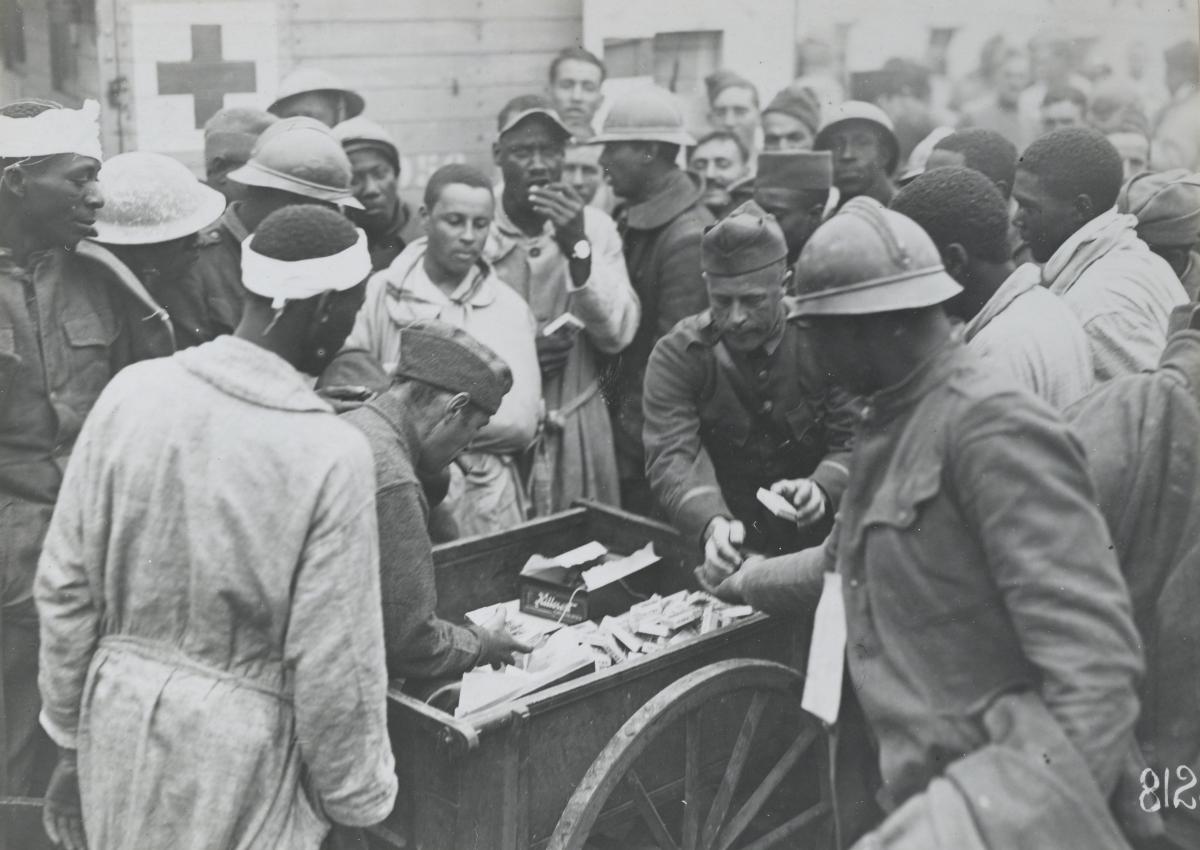 soldiers gather around a cart of chocolate, cigarettes, etc