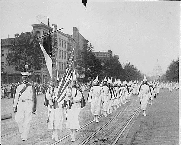 KKK members march down Pennsylvania ave in white robes, Capitol building in background