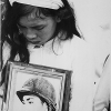 Young widow with photo of her missing husband, at mass funeral service for Tet victims in Hue