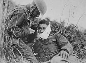 Soldier of Company K, 110th Regiment Infantry, just wounded, receiving first-aid treatment from a comrade. Varennes-en-Argonne, France.